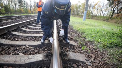 Сотрудник в форме осматривает рельс, рядом работник в оранжевом жилете