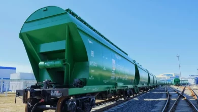 Зелёный вагон-хоппер в составе поезда на станционных путях