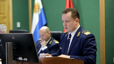 Мужчина в форме железнодорожника выступает за трибуной в зале заседаний