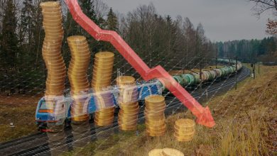 Стопки монет и стрелка падения на фоне поезда