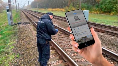 Человек в форме у путей и рука со смартфоном