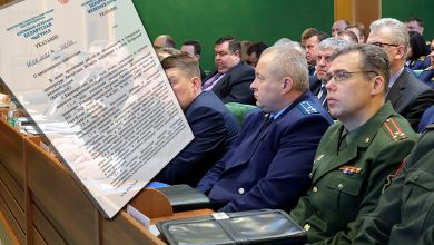 Участники совещания, в том числе военные, в зале, на переднем плане документ