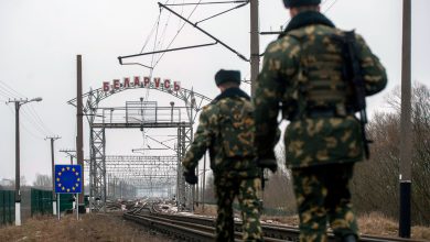 Двое пограничников у путей на пограничном переходе с аркой «Беларусь» и знаком ЕС