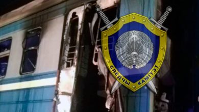 Эмблема Следственного комитета на фоне повреждённого вагона электропоезда