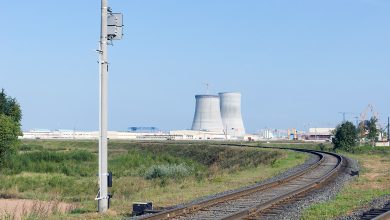 Железнодорожный путь и светофор, вдали градирни атомной электростанции