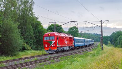 Пассажирский поезд с красным тепловозом на перегоне летом