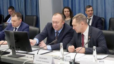 Участники совещания за столом с микрофонами и мониторами