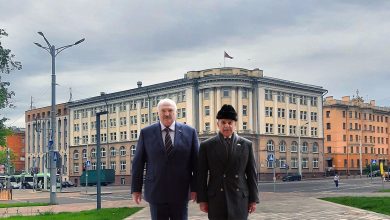 Двое мужчин в пальто на площади перед административным зданием