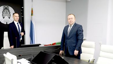 Двое мужчин в деловых костюмах в кабинете с гербом Беларуси и флагами
