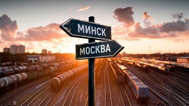 Указатели «Минск» и «Москва» на фоне путей грузовой станции с составами на закате